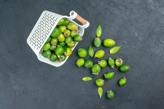 Draufsicht frische Feijoas verstreut vom Plastikkorb auf dunkler Oberfläche mit Kopierplatz