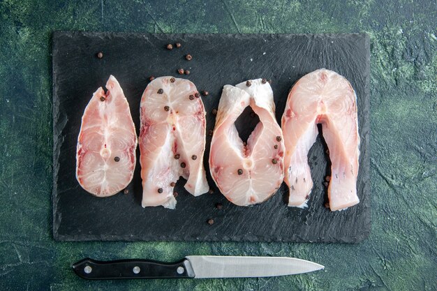 Draufsicht frische Fischscheiben auf dunklem Tisch Ozeanfleisch Meeresfrüchte Gericht Meeresmehl Wasser Lebensmittel Pfeffer