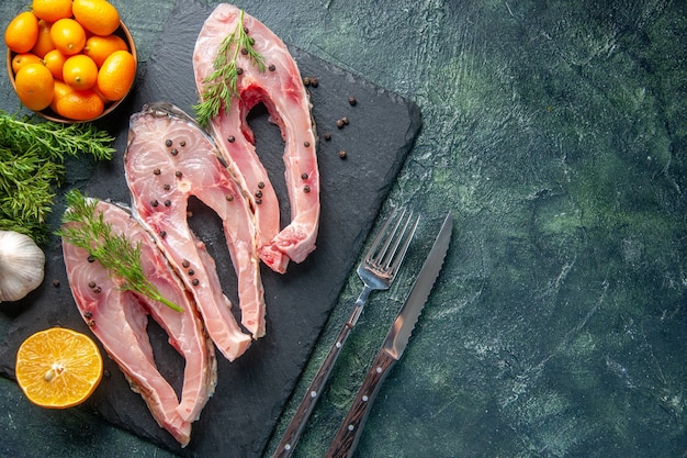 Draufsicht frische Fischscheiben mit Grüns und Kumquats auf dunklem Hintergrund