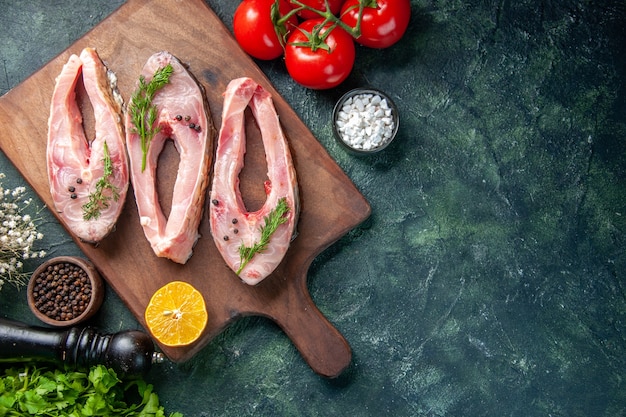 Draufsicht frische Fischscheiben mit Grüns und Tomaten auf dunklem Hintergrund