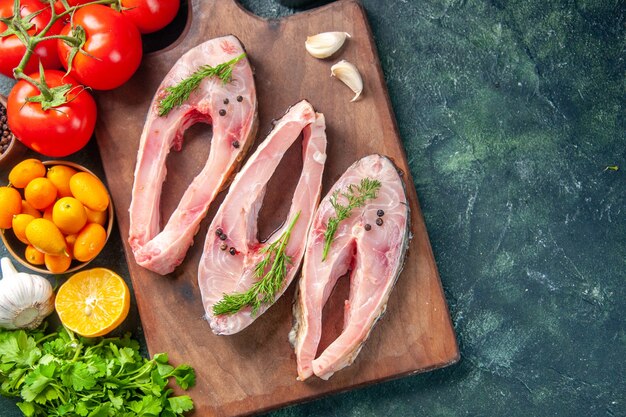 Draufsicht frische Fischscheiben mit Grüns und Tomaten auf dunklem Hintergrund