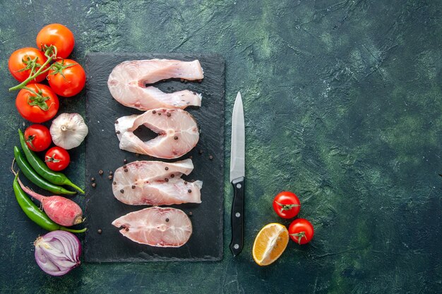 Draufsicht frische Fischscheiben mit roten Tomaten auf dunklem Hintergrund Ozeanfleisch Meeresfrüchte Mahlzeit Wasser Essen Pfeffer Gericht