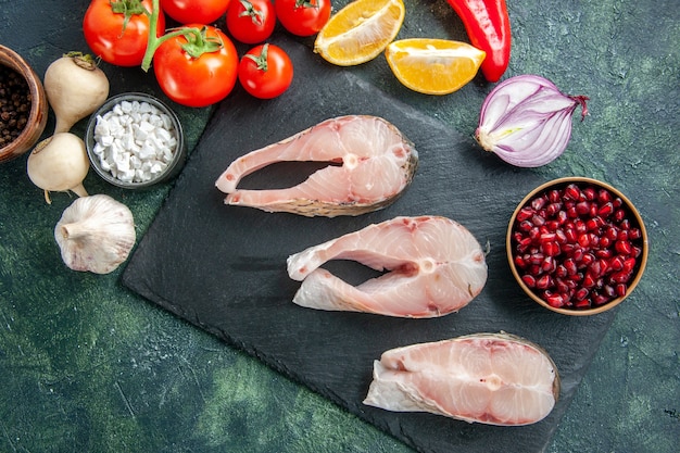 Draufsicht frische Fischscheiben mit roten Tomaten auf einem dunklen Tisch Meeresfrüchte Meeresfleisch Meeresfrüchte Gericht Essen Salat Wasser Pfeffer