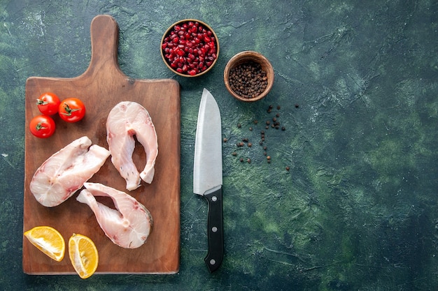 Draufsicht frische Fischscheiben mit Tomaten und Zitrone auf dunklem Hintergrund Meeresfrüchte Ozeanfleisch Meeresmehl Wasser Pfeffer Gericht Essen freien Raum