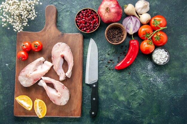 Draufsicht frische Fischscheiben mit Tomaten und Zitrone auf dunklem Hintergrund Meeresfrüchte Ozeanfleisch Meerwasser Pfeffer Gericht Essen