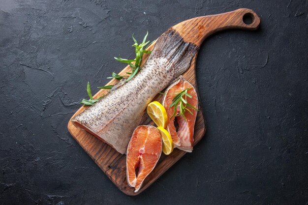 Draufsicht frische Fischscheiben mit Zitrone auf dunklem Hintergrund Farbe Wasser Foto Fleisch Lebensmittel Meer Gesundheit Abendessen Mahlzeit Meeresfrüchte