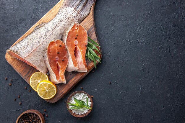 Draufsicht frische Fischscheiben mit Zitrone auf dunklem Hintergrund Meeresfrüchte Gesundheit Fleisch Farbe Wasser Essen Abendessen Meer Mahlzeit Restaurant freier Raum