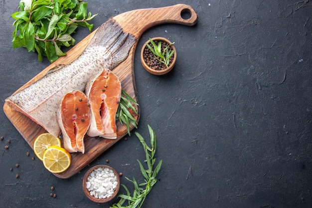 Draufsicht frische Fischscheiben mit Zitrone und Gemüse auf dunklem Hintergrund Meeresfrüchte Gesundheit Fleisch Abendessen Ozeanmahlzeit Restaurant Essen