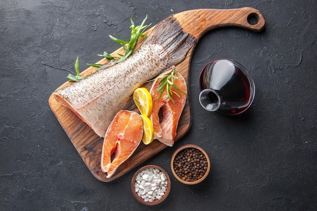 Draufsicht frische Fischscheiben mit Zitrone und Wein auf dunklem Hintergrund Farbe Wasser Fleisch Lebensmittel Ozean Gesundheit Abendessen Mahlzeit Meeresfrüchte
