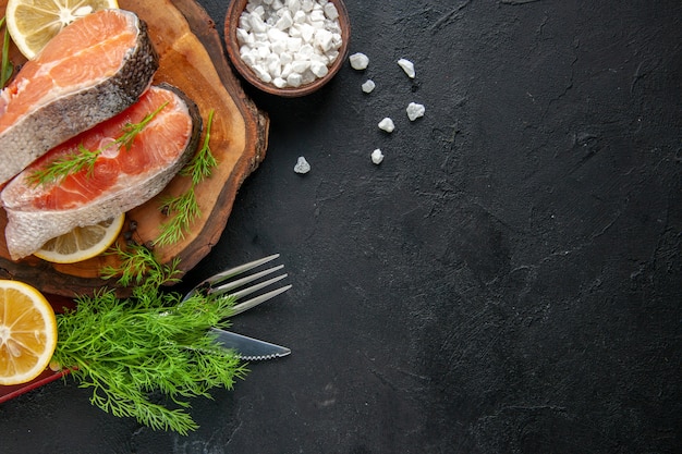 Draufsicht frische Fischscheiben mit Zitronenscheiben auf dunklem Tisch