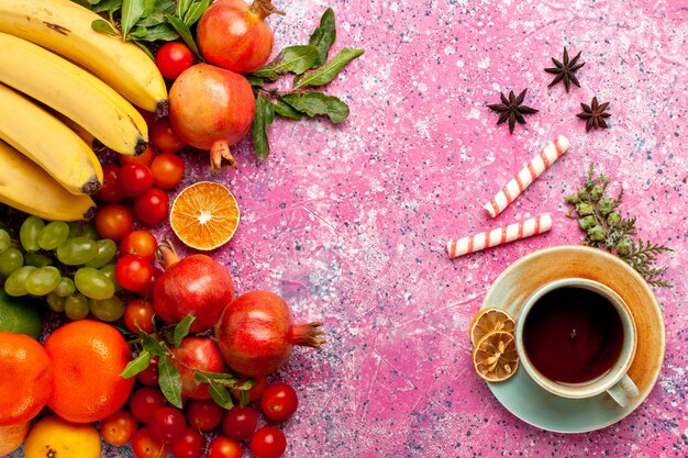 Kostenloses Foto draufsicht frische fruchtzusammensetzung mit tasse tee auf hellrosa schreibtisch