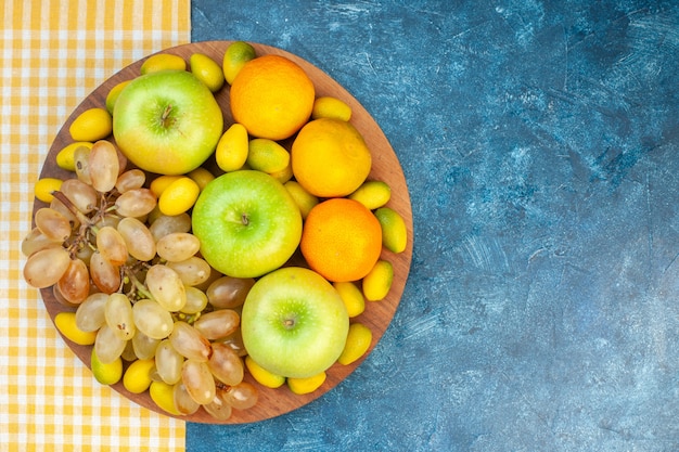 Draufsicht frische früchte äpfel mandarinen und trauben auf blauem tisch