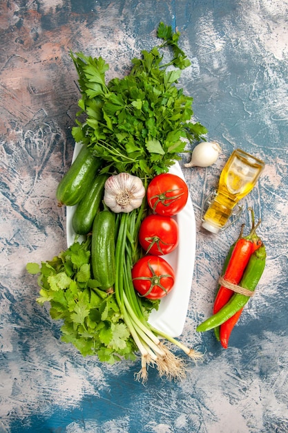 Draufsicht frische Frühlingszwiebel mit Tomaten und Grüns auf hellblauem Hintergrund