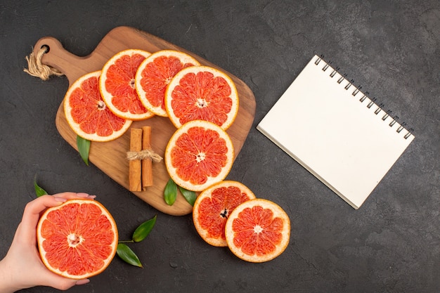 Kostenloses Foto draufsicht frische grapefruitscheiben auf dunklem hintergrund