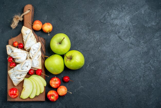 Draufsicht frische grüne Äpfel mit süßem Gebäck auf dunkelgrauem Hintergrundfrucht süßer Kekszuckerplätzchenkuchen