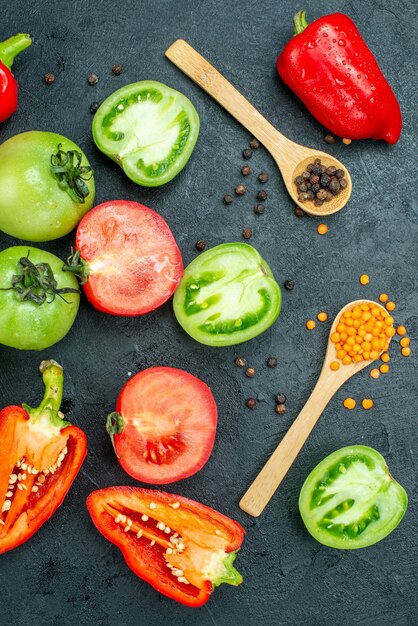 Draufsicht frische grüne Tomaten rote Paprika gemütliche rote Linsen und schwarzer Pfeffer auf dunklem Hintergrund