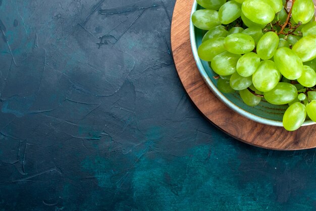 Draufsicht frische grüne Trauben milde saftige Früchte innerhalb Platte auf dem dunkelblauen Schreibtisch.