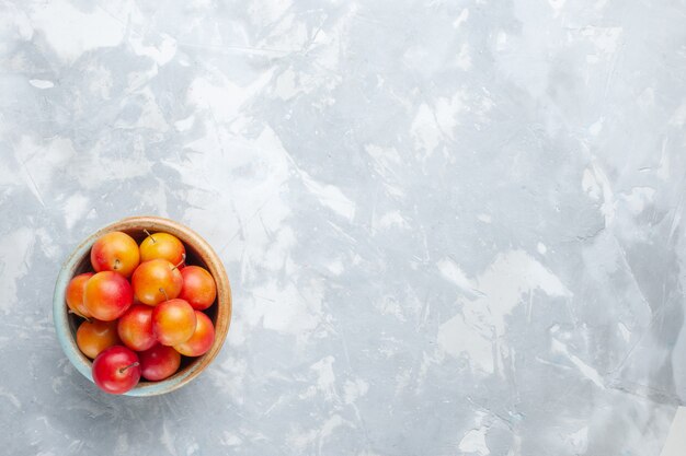 Draufsicht frische Kirschpflaumen sauer und frisch im Topf auf weißem Schreibtisch Obst sauer frisch weich