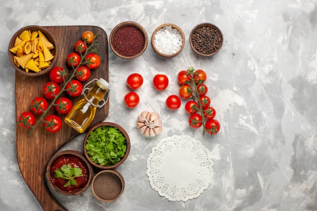 Draufsicht frische Kirschtomaten mit Gewürzen und Grüns auf weißem Schreibtisch