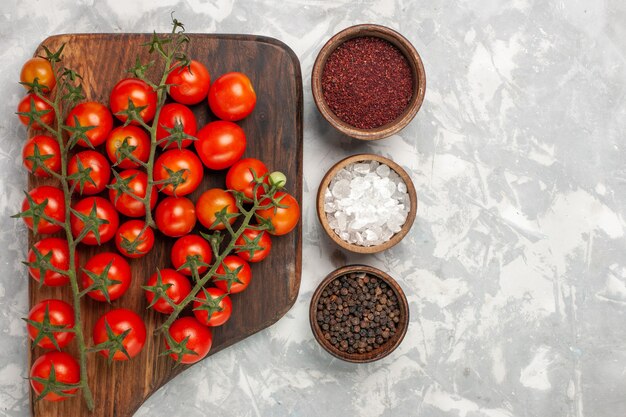 Draufsicht frische Kirschtomaten reifes ganzes Gemüse mit Gewürzen auf weißer Oberfläche