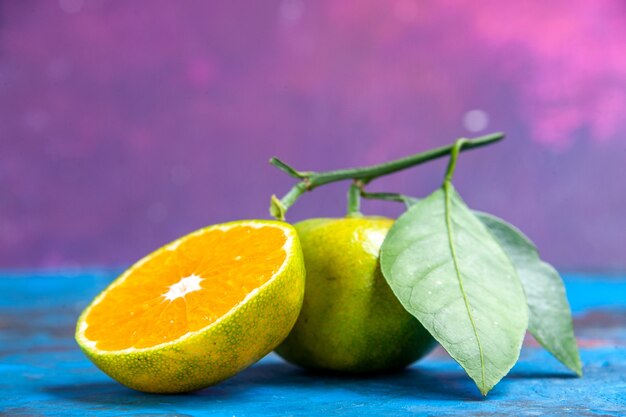 Draufsicht frische Mandarine mit Blättern und geschnittener Mandarine auf blau-rosa Oberfläche freiem Raum