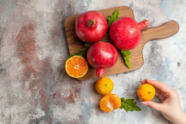 Draufsicht frische Mandarinen mit roten Granatäpfeln auf hellem Hintergrund