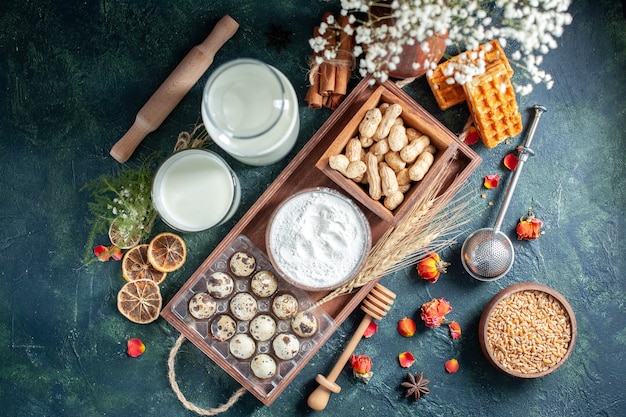 Draufsicht frische Milch mit Keksen Eiern und Nüssen auf dunkelblauem Hintergrund Teig backen Kuchen Keks Kuchen Brötchen Zucker Dessert