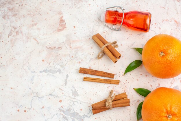 Draufsicht frische Orangen-Zimtstangenflasche auf heller Oberfläche mit Kopierraum