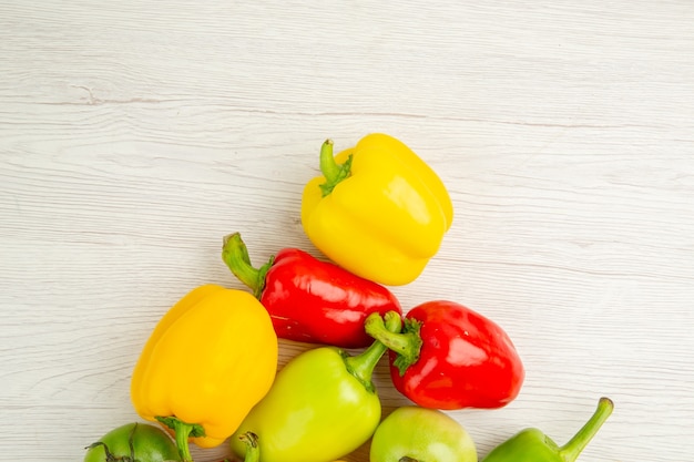 Kostenloses Foto draufsicht frische paprika unterschiedlich gefärbt auf dem weißen hintergrund reife mahlzeit salatfarbe salad