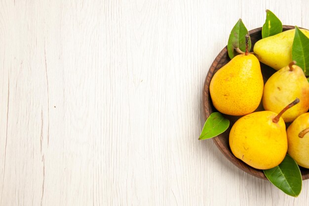 Draufsicht frische reife Birnen süße Früchte im Teller auf weißem Schreibtisch Obst gelb frisch süß reif