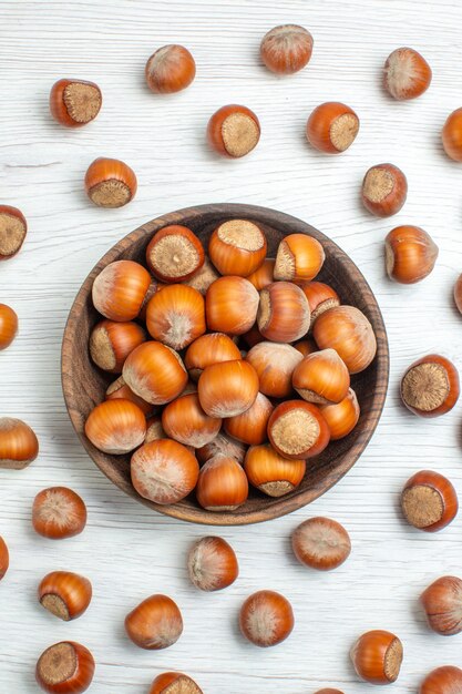 Draufsicht frische rohe Haselnüsse auf einem weißen Schreibtisch Nuss Snack Film Pflanzennahrung Walnuss