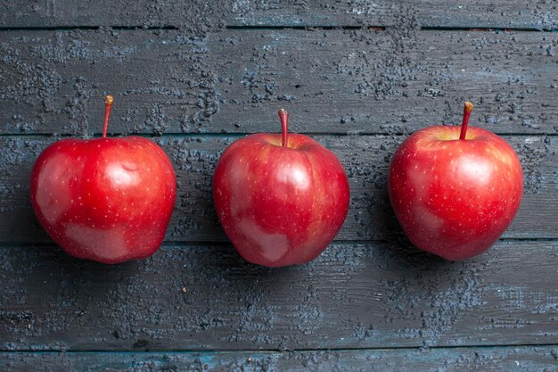 Kostenloses Foto draufsicht frische rote äpfel reife und weiche früchte auf dunkelblauem boden gesäumt viele früchte roter frischer pflanzenfarbbaum