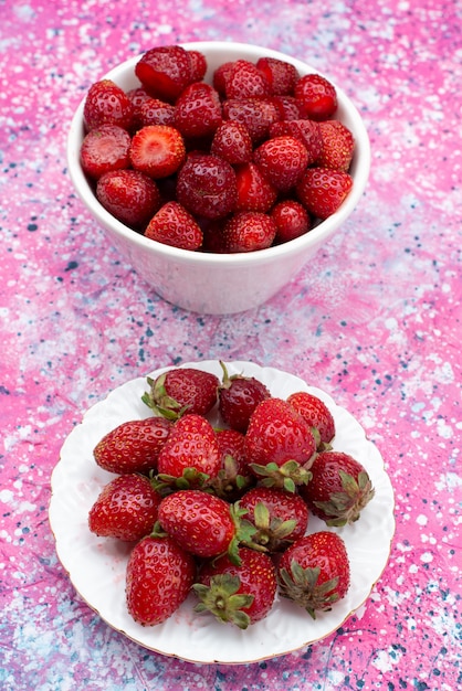 Draufsicht frische rote Erdbeeren innerhalb der weißen Platten auf dem farbigen Hintergrundfruchtbeerenfarbvitamin