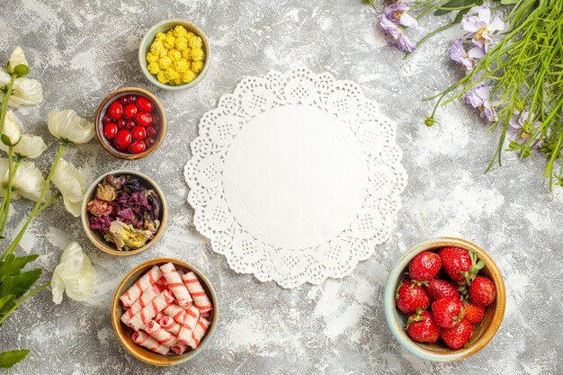 Draufsicht frische rote Erdbeeren mit Bonbons auf weißer Bodenfarbe Beerenfruchtbonbons