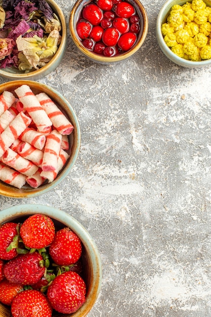 Draufsicht frische rote Erdbeeren mit Bonbons auf weißer Oberfläche Beerenfrucht rote Bonbons