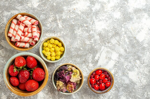 Draufsicht frische rote Erdbeeren mit Bonbons auf weißer Oberfläche Früchte süße Bonbonfarbe