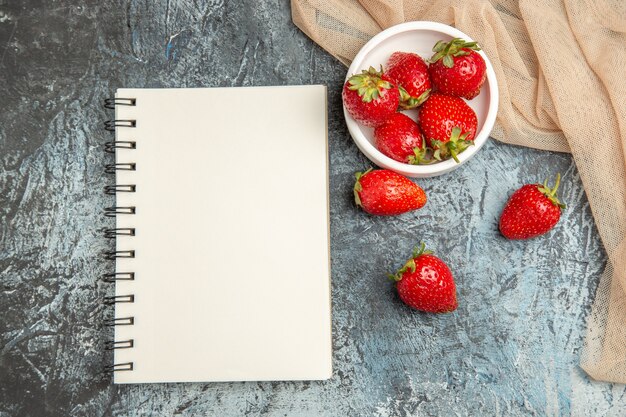 Draufsicht frische rote Erdbeeren mit Notizblock auf dunkelheller Oberfläche rote Fruchtbeere