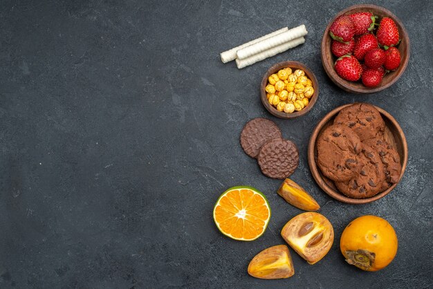 Draufsicht frische rote Erdbeeren mit süßen Keksen auf dunklem Tisch, frischer Zuckerkeks