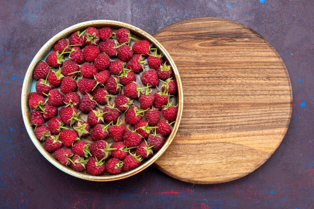 Draufsicht frische rote Himbeeren reife Beeren auf dem dunkelblauen Schreibtisch Beerenfrucht milden Sommer