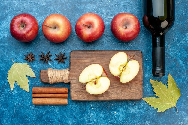 Draufsicht frische rote Äpfel mit einer Flasche Wein auf dem blauen Tisch reife Fruchtalkoholfarbfotobaum