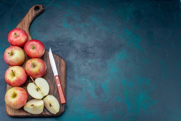 Draufsicht frische rote Äpfel saftig und weich mit braunem Schreibtisch auf dem dunkelblauen Hintergrund reifes Obst frisches mildes Vitamin