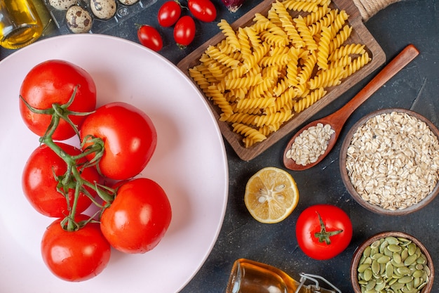 Draufsicht frische rote tomaten mit rohen nudelgemüse-gewürzen und eiern auf einem dunklen tisch farbe öl kalorien essen ei milchteig abendessen mahlzeit