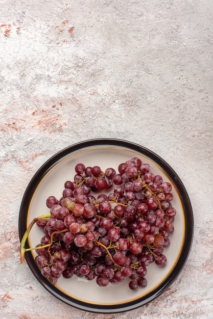 Kostenloses Foto draufsicht frische rote trauben saftige und milde früchte innerhalb platte auf weißer oberfläche