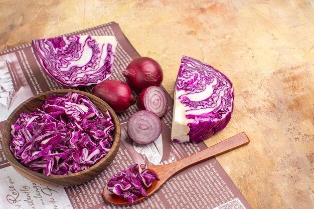 Draufsicht frische rote Zwiebeln und eine Schüssel mit gehacktem Rotkohl für Gemüsesalat auf Holzhintergrund mit Kopierplatz