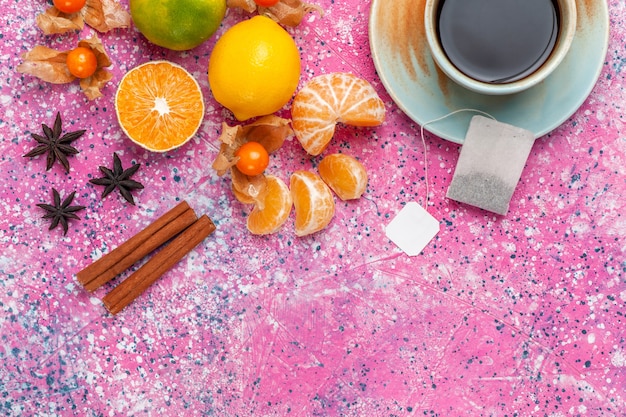 Kostenloses Foto draufsicht frische saure mandarinen mit zitronen und tasse tee auf rosa hintergrund.