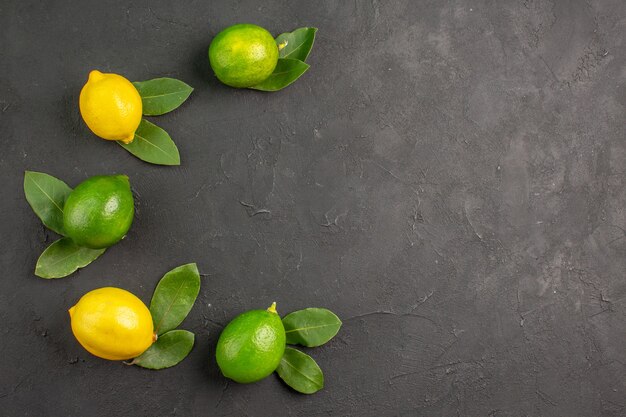 Draufsicht frische saure Zitronen auf dem dunklen Tischfrucht-Limetten-Zitrus