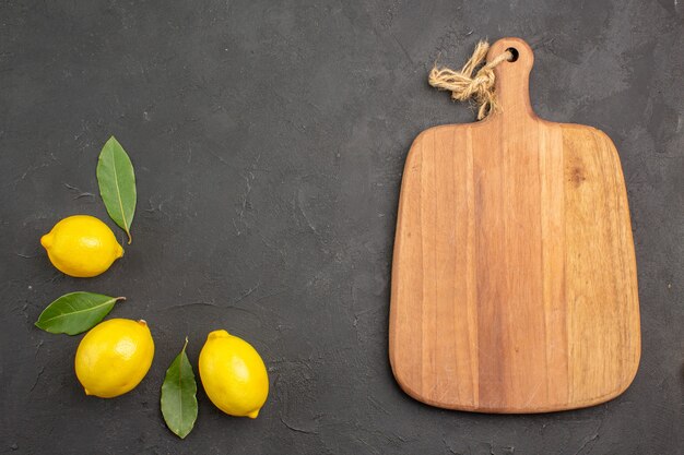 Draufsicht frische saure Zitronen mit Blättern auf dem dunklen Tischfrucht limettengelbe Zitrusfrüchte