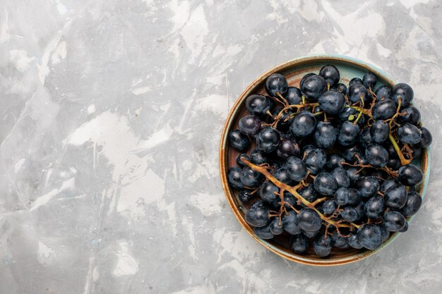 Draufsicht frische schwarze Trauben saftige milde süße Früchte auf dem hellweißen Schreibtisch