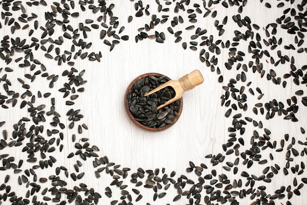 Draufsicht frische Sonnenblumenkerne schwarze Samen auf weißer Oberfläche Samenmais-Snack-Öl viele Fotos