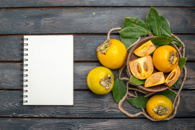 Draufsicht frische süße Kakis auf hölzernem rustikalem Tisch, schmecken reife Früchte